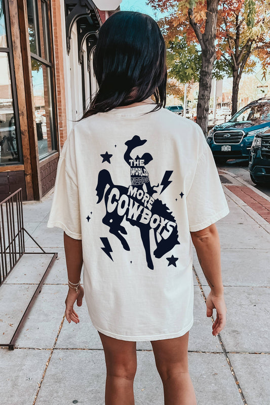 Person wearing a white t-shirt with a 'The World Needs More Cowboys' graphic.